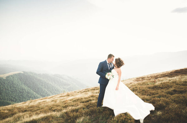Beautifull wedding couple kissing and embracing near mountain with perfect view.