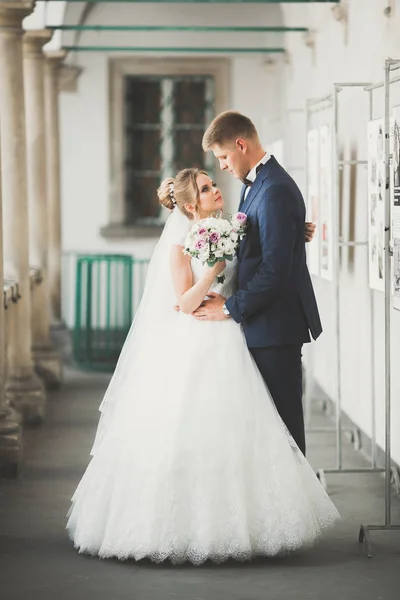 Ravissant couple de mariage heureux, mariée avec longue robe blanche posant dans la belle ville — Photo