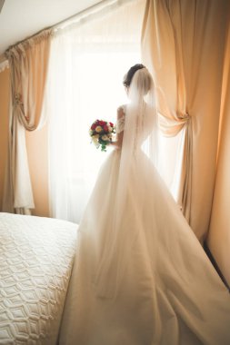 Beyaz elbiseli lüks gelin düğün törenine hazırlanırken poz veriyor.