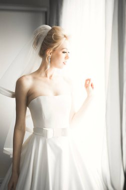 Beyaz elbiseli lüks gelin düğün törenine hazırlanırken poz veriyor.