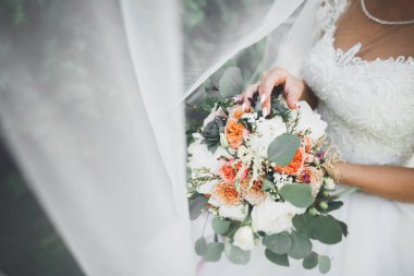 Gelin çiçekli büyük ve güzel bir düğün buketi tutuyor.