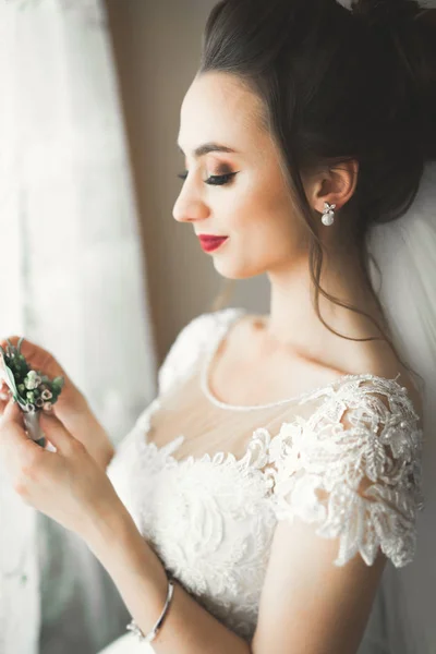 Hermosa novia con vestido de novia de moda con plumas con maquillaje de lujo deleite y peinado, estudio sesión de fotos interior —  Fotos de Stock