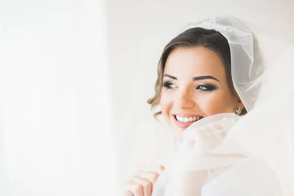 Prachtige bruid in badjas poseren en voor te bereiden op de bruiloft ceremonie gezicht in een kamer — Stockfoto