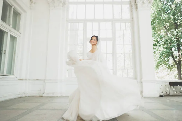 美丽的新娘穿着婚纱时有长时间充分的裙子，白色背景，跳舞和微笑 — 图库照片