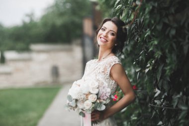 Gelin çiçekli büyük ve güzel bir düğün buketi tutuyor.