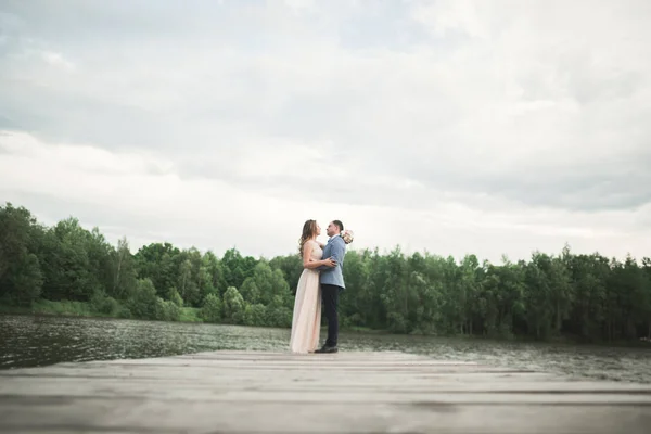 Mariée et marié marchant sur la rivière, souriant, embrassant — Photo