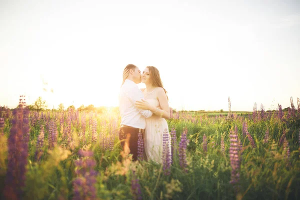 Casal lindo, amor ao pôr-do-sol. Fielf com flores — Fotografia de Stock