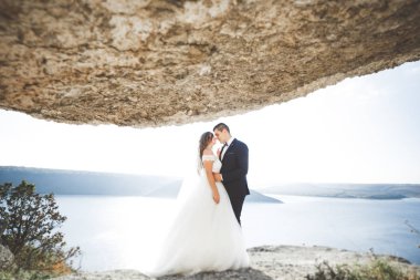 Güzel bir sahilde poz veren genç bir çiftin mutlu ve romantik sahnesi.