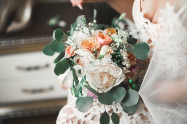 Gelin çiçekli büyük ve güzel bir düğün buketi tutuyor.