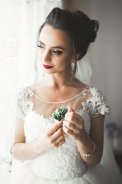 Cüppeli muhteşem gelin bir odada düğün töreni için poz veriyor ve hazırlanıyor.