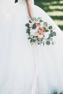 Gelin çiçekli büyük ve güzel bir düğün buketi tutuyor.