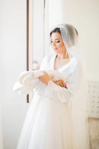 Linda noiva em roupão posando e se preparando para o rosto cerimônia de casamento em uma sala — Fotografia de Stock