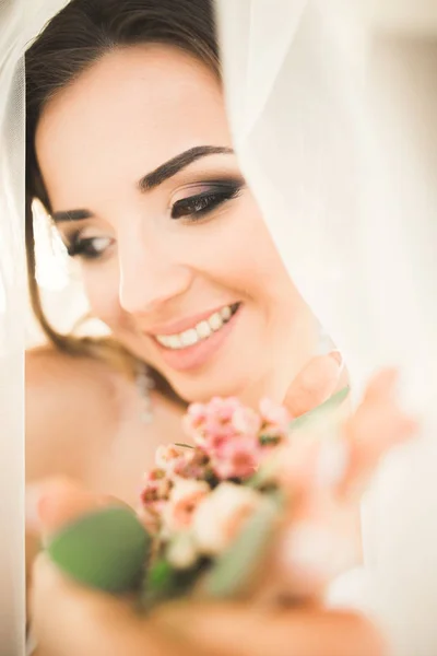 Preciosa novia en bata posando y preparándose para la ceremonia de boda cara en una habitación —  Fotos de Stock