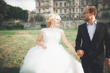 Güzel, romantik bir düğün. Yeni evliler. Eski kalenin yakınlarında sarılıyorlar.