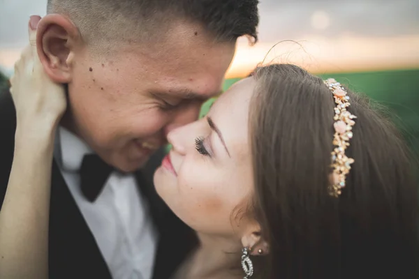 Bruiloft, mooie romantische bruid en bruidegom kussen omhelzen bij zonsondergang — Stockfoto