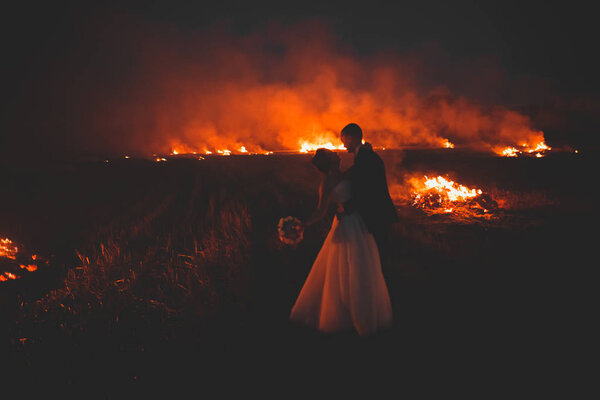 Amazing wedding couple near the fire at night.