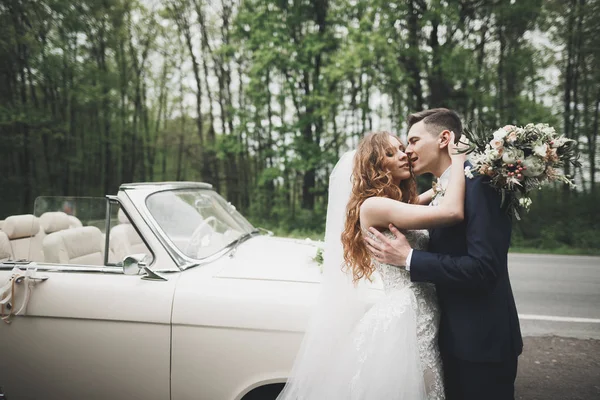 Stylish wedding couple, bride, groom kissing and hugging on retro car — Stock Photo, Image