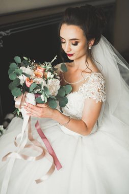 Cüppeli muhteşem gelin bir odada düğün töreni için poz veriyor ve hazırlanıyor.