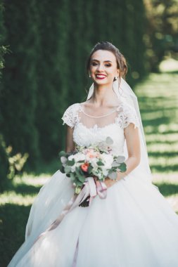 Parkta poz veren zarif beyaz elbiseli güzel gelin.