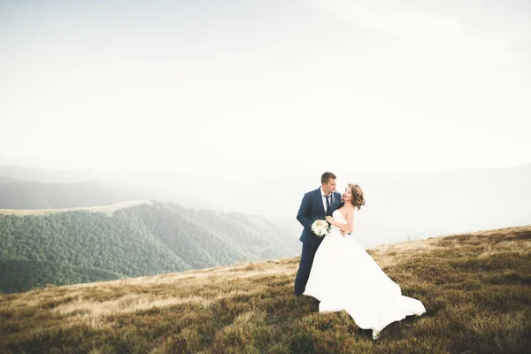 Schönes Hochzeitspaar posiert bei Sonnenuntergang auf einem Berg — Stockfoto