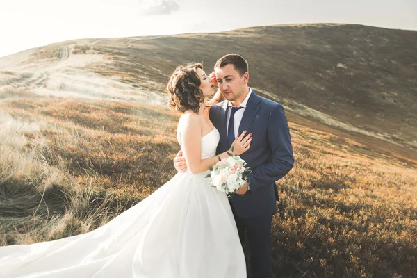 Joyeux beau couple de mariage mariée et marié le jour du mariage à l'extérieur sur le rocher des montagnes. Couple mariage heureux en plein air sur la nature, douces lumières ensoleillées — Photo