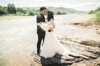 Zarif nazik şık damat ve gelin taşlarla Nehri yakınında. Evlilik çift aşık