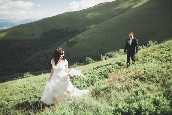 Jovem casal recém-casado, noiva e noivo beijando, abraçando na visão perfeita das montanhas, céu azul — Fotografia de Stock