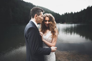 Güzel dağlarda poz veren mutlu bir düğün çifti.