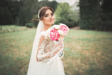 Parkta poz veren zarif beyaz elbiseli güzel gelin.