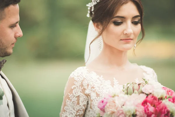 Casal elegante de recém-casados felizes andando no parque em seu dia de casamento com buquê — Fotografia de Stock