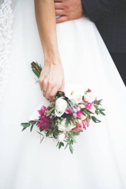 Gelin çiçekli büyük ve güzel bir düğün buketi tutuyor.
