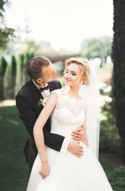 Yeni evli çiftimiz düğün günlerinde ellerinde buketle parkta yürüyorlar.