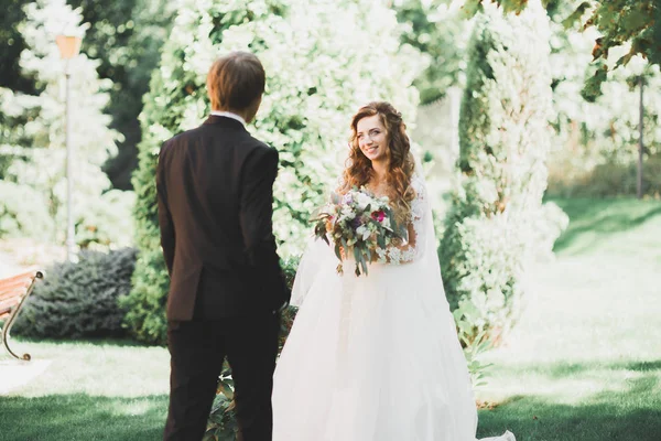 Stijlvol paar gelukkige pasgetrouwden wandelen in het park op hun trouwdag met boeket — Stockfoto