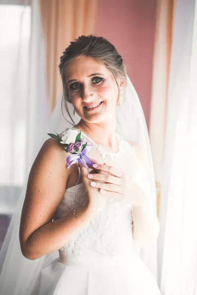 Hermosa novia con vestido de novia de moda con plumas con maquillaje de lujo deleite y peinado, estudio sesión de fotos interior — Foto de Stock