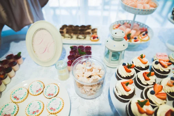 Läckra och välsmakande dessert bord med cupcakes skott i receptionen närbild — Stockfoto