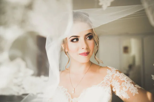 Великолепная невеста в халате позирует и готовится к свадебной церемонии лицо в комнате — стоковое фото