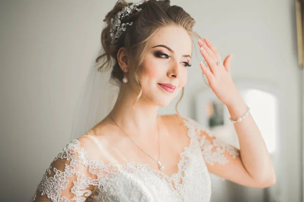 Preciosa novia en bata posando y preparándose para la ceremonia de boda cara en una habitación — Foto de Stock