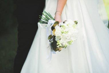 Gelin çiçekli büyük ve güzel bir düğün buketi tutuyor.