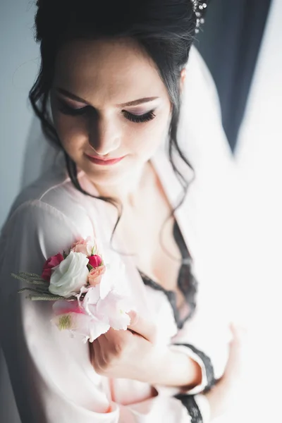 Preciosa novia en bata posando y preparándose para la ceremonia de boda cara en una habitación — Foto de Stock