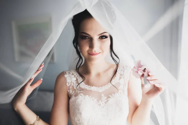 Preciosa novia en bata posando y preparándose para la ceremonia de boda cara en una habitación —  Fotos de Stock