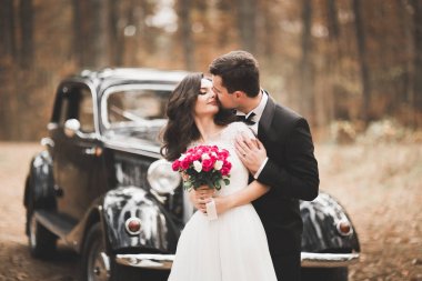 Güzel düğün çifti görkemli retro arabanın yakınında poz
