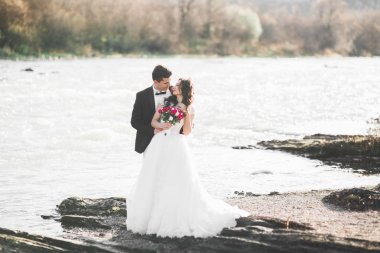 Düğün çifti, damat ve gelin kucaklaşıyor, nehir kenarında.