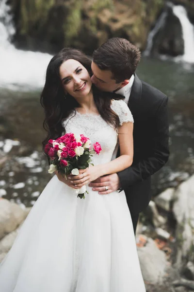 Елегантна стильна щаслива брюнетка наречена і чудовий наречений на тлі красивої річки в горах — стокове фото