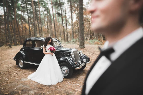 Hermosa pareja de boda posando cerca de espléndido coche retro — Foto de Stock