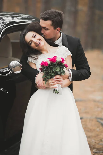 Beautiful wedding couple posing near splendid retro car — Stock Photo, Image