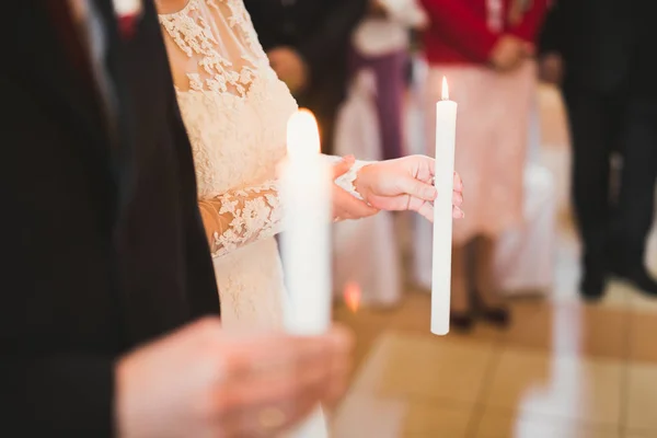 Panna młoda i pan młody trzymający świece w kościele — Zdjęcie stockowe