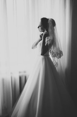 Cüppeli muhteşem gelin bir odada düğün töreni için poz veriyor ve hazırlanıyor.