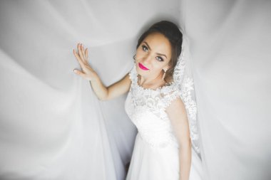 Cüppeli muhteşem gelin bir odada düğün töreni için poz veriyor ve hazırlanıyor.