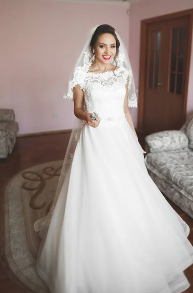 Preciosa novia en bata posando y preparándose para la ceremonia de boda cara en una habitación — Foto de Stock