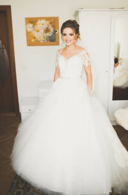 Cüppeli muhteşem gelin bir odada düğün töreni için poz veriyor ve hazırlanıyor.